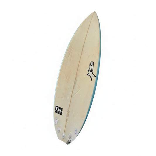 A natural wood surfboard with a light blue edge, featuring a black star logo and a 'Gs' brand patch, shown against a plain white background.