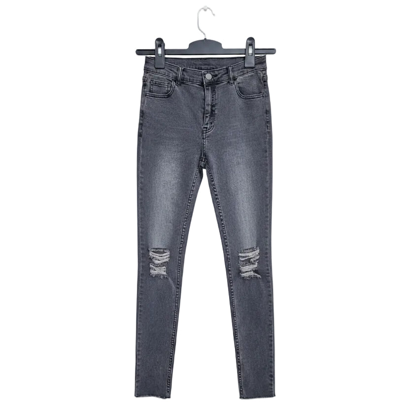 Black distressed jeans on a hanger against a textured wall background