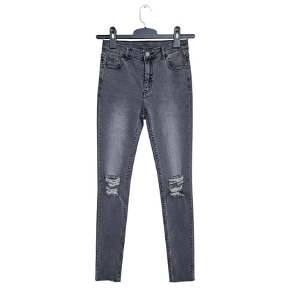 Black distressed jeans on a hanger against a textured wall background