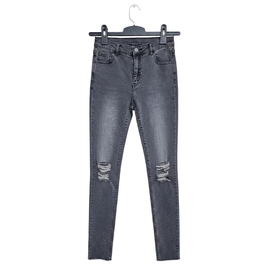 Black distressed jeans on a hanger against a textured wall background
