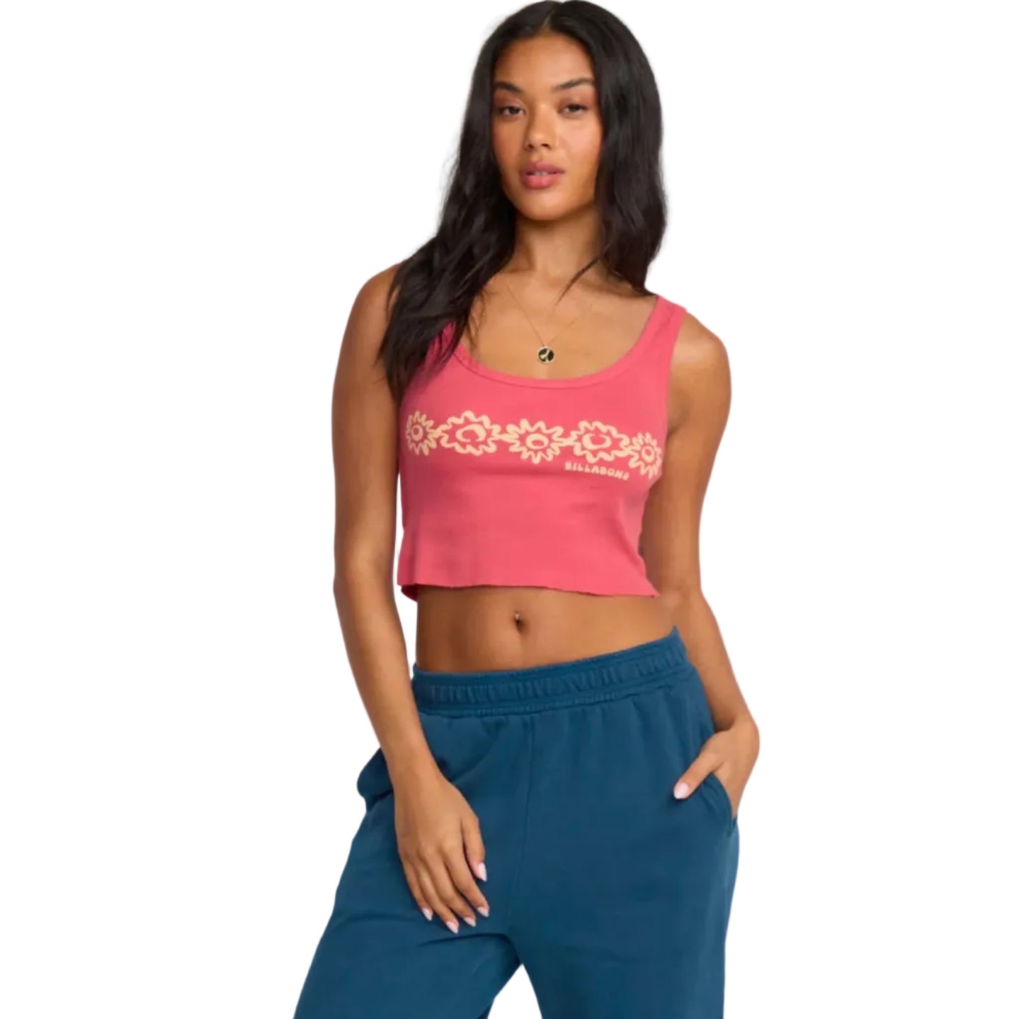 Woman wearing a pink crop top with floral design and blue pants on a plain background