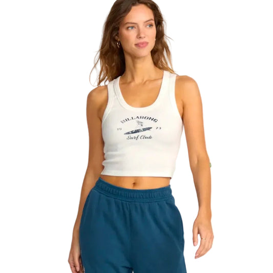 Woman wearing a white tank top with a logo and text, standing against a plain background