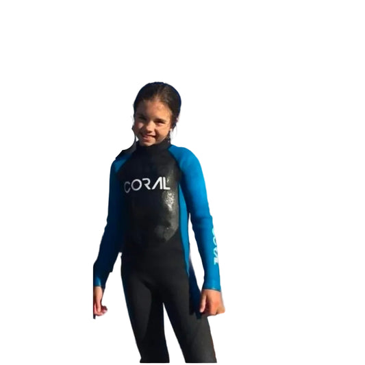 Child in a wetsuit on a beach with a clear blue sky