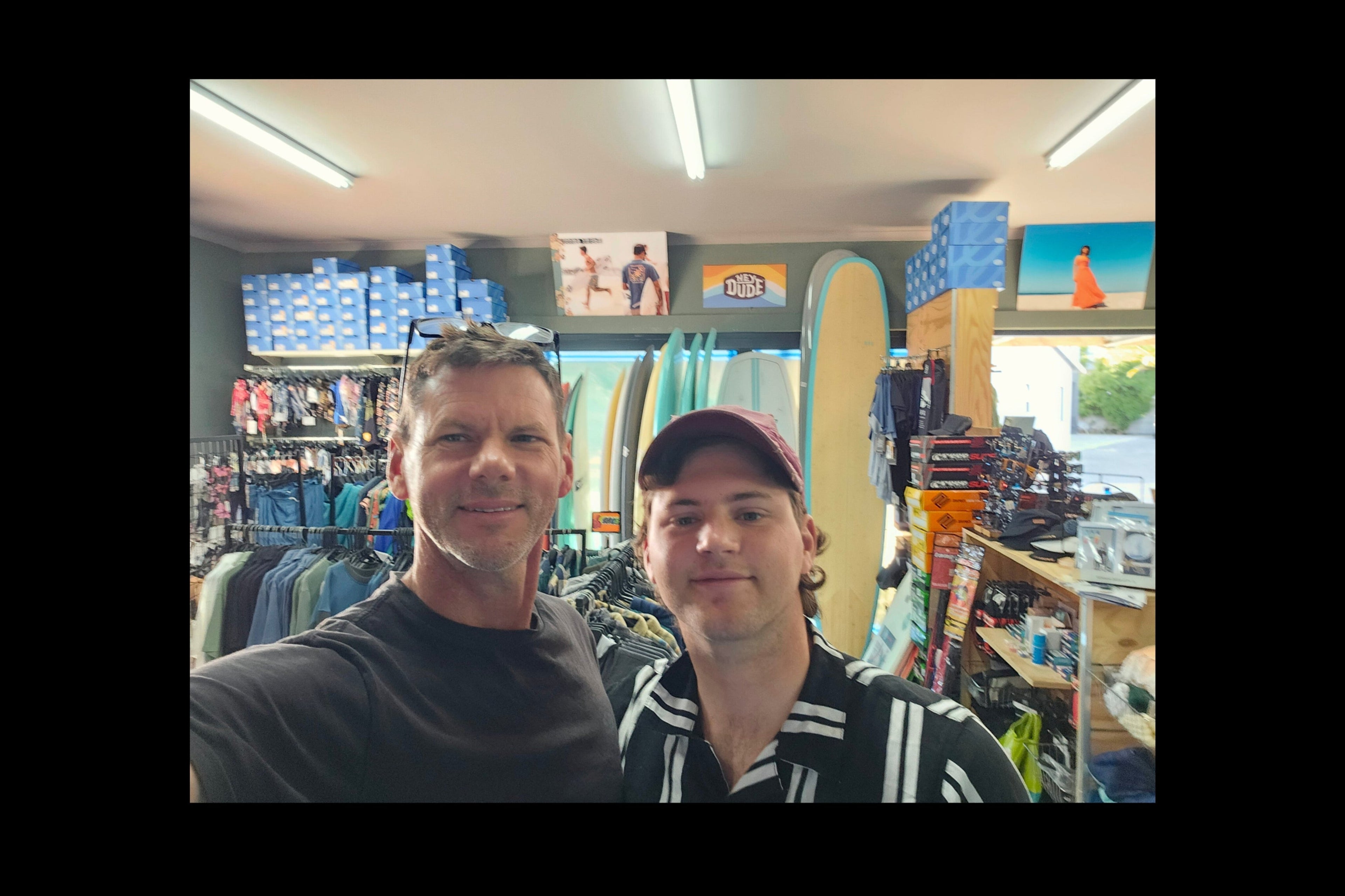 Father and Son business posing for a photo in a store with various items on shelves.