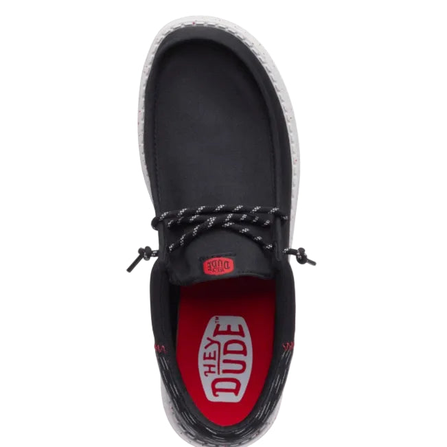 Black shoe with red sole and 'Hey Dude' branding on a white background