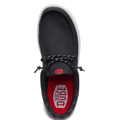 Black shoe with red sole and 'Hey Dude' branding on a white background