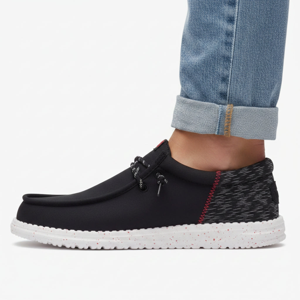 Black slip-on shoe with white sole on a white background