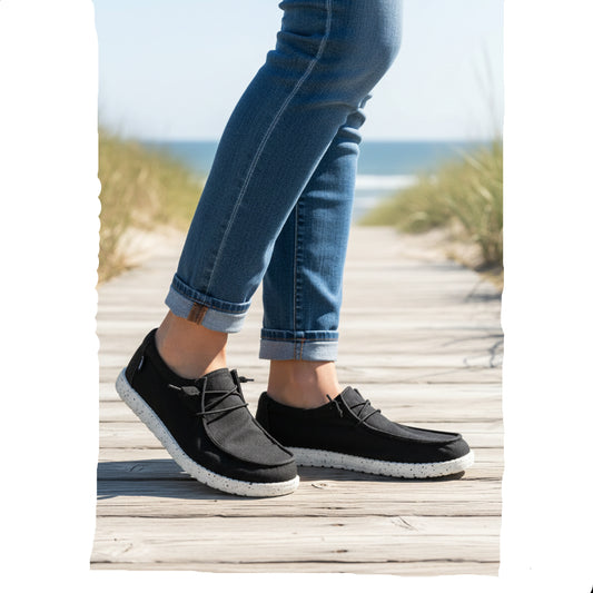 Black shoes with white soles on a light gray surface