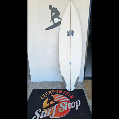 White surfboard with 'Good Hope' branding on a mat with 'Yzerfontein Surf Shop' logo.
