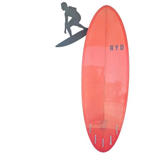Orange surfboard with 'RYD' branding on a mat in front of a wall with a silhouette of a person on a surfboard.