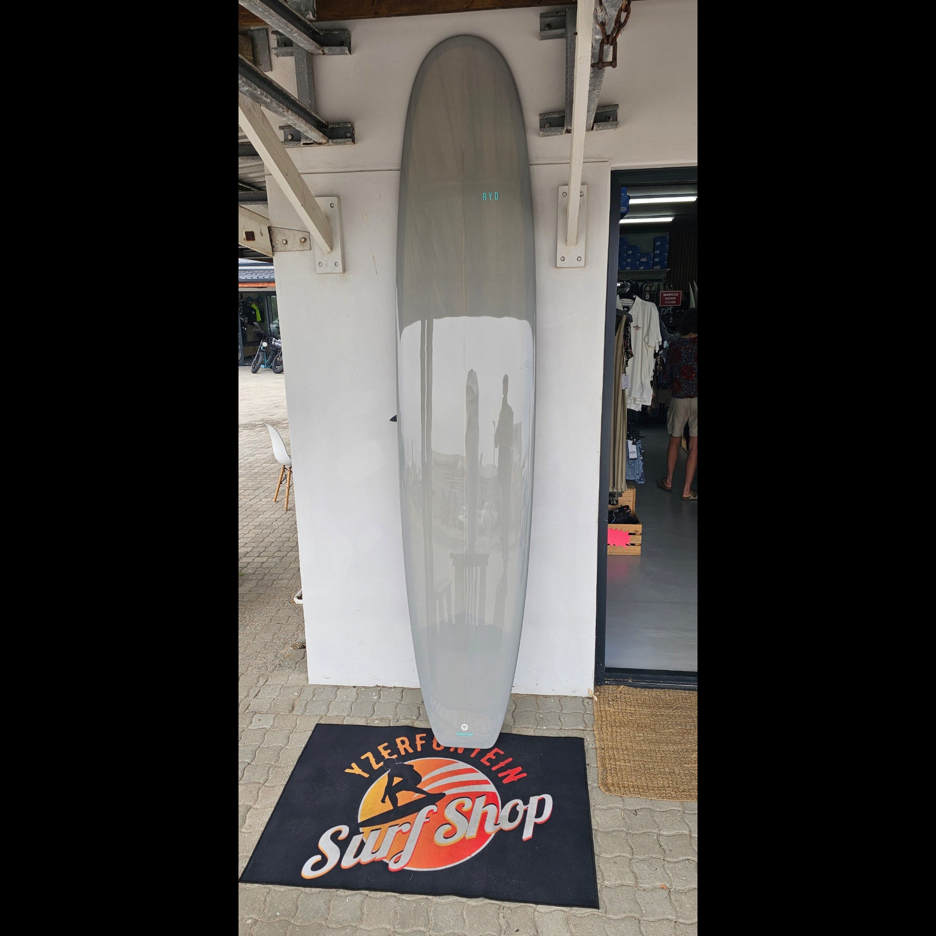 Longboard on a white surface with a branded mat in the background
