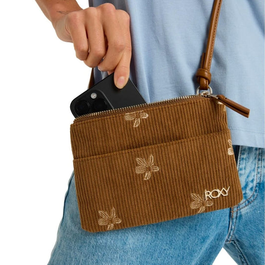 Brown crossbody bag with floral embroidery held by a person wearing a light blue shirt and jeans.