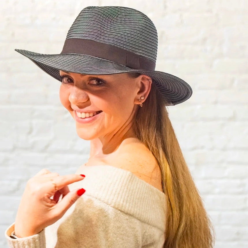 Woman wearing a wide-brimmed hat with a neutral background