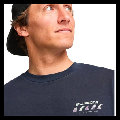 Man wearing a black cap and navy Billabong t-shirt on a white background