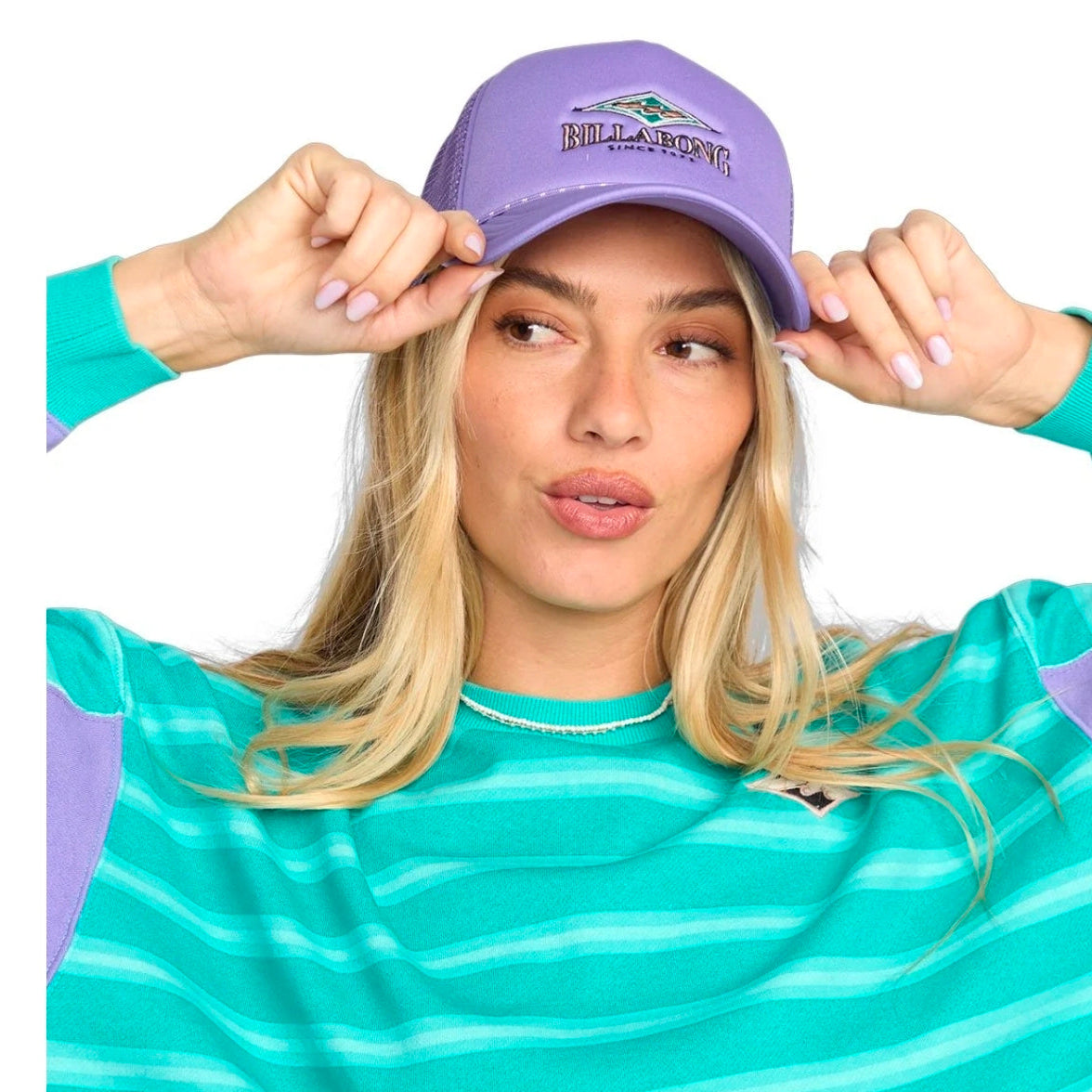 Woman wearing a purple cap with 'Billabong' logo and a teal striped shirt.