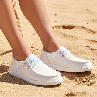 White sneakers worn on a sandy surface