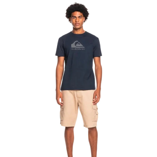 Man wearing a navy blue t-shirt with a logo and beige cargo shorts on a white background