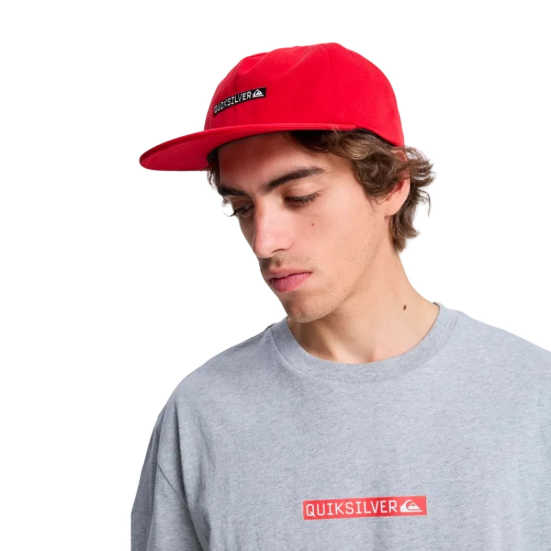 Person wearing a red Quiksilver cap and gray t-shirt with a red logo on a white background