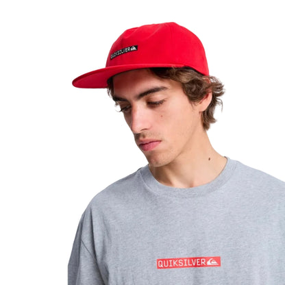 Person wearing a red Quiksilver cap and gray t-shirt with a red logo on a white background