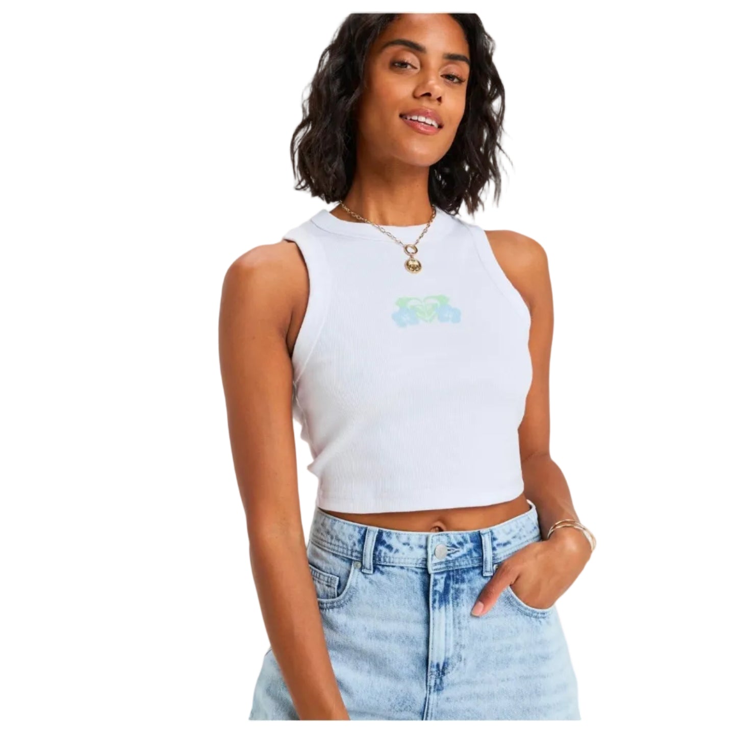 Woman wearing a white sleeveless top with a graphic design and light blue jeans on a plain background
